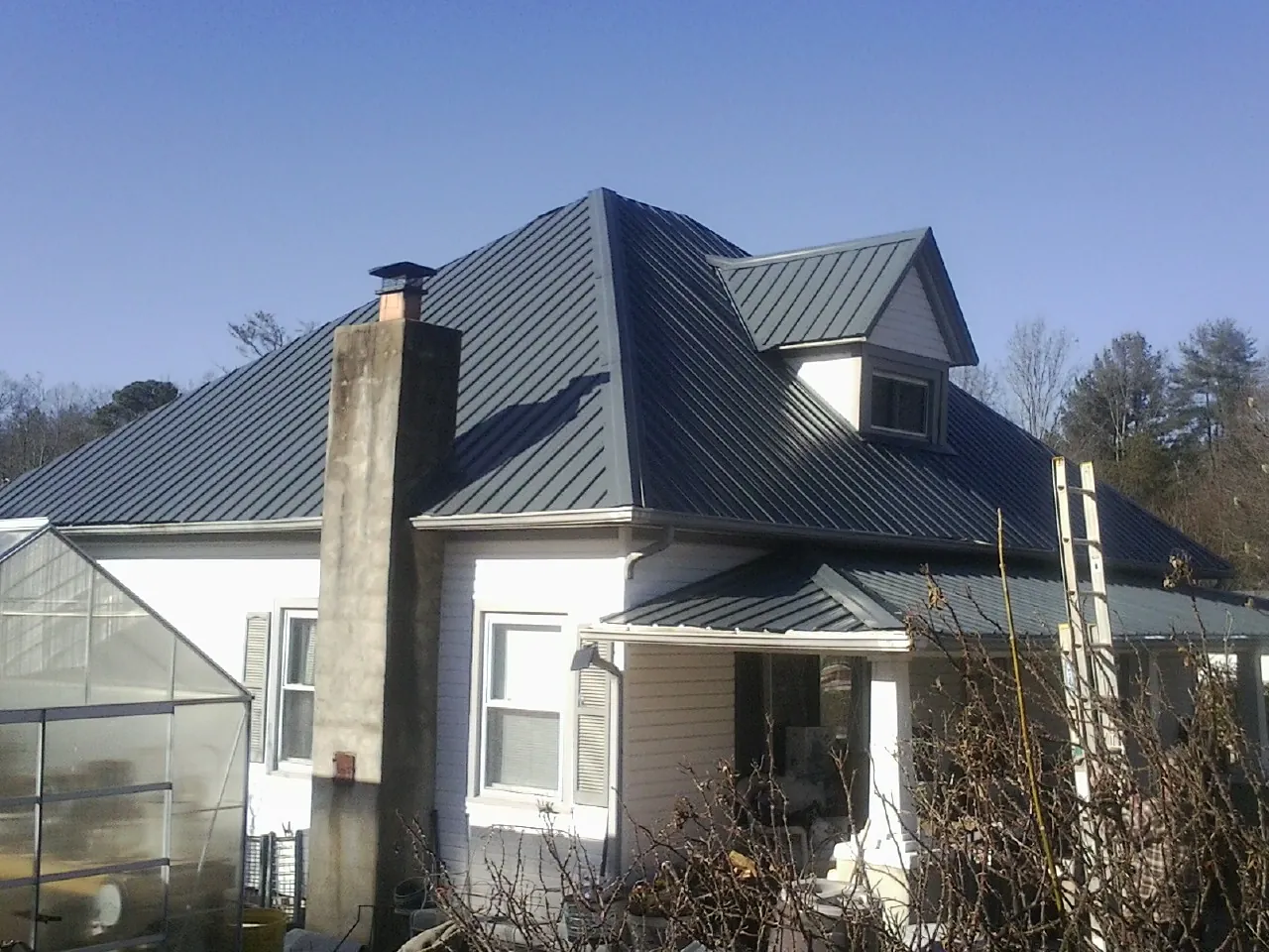Dark blue standing seam metal roof on a white farmhouse with dormer — Slate & Tile Roof Repair by Roofing Brothers in Boylston