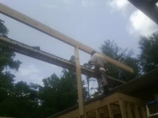 Carpenter setting a ridge beam over a new addition frame — Ice Dam Removal by Roofing Brothers in Boylston