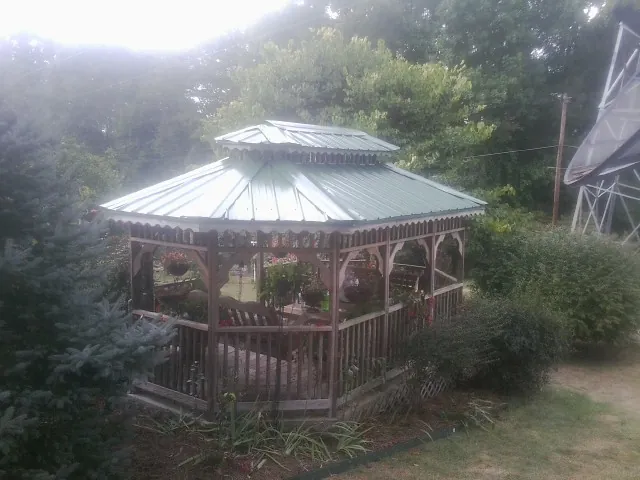 Green metal roof on a backyard gazebo surrounded by garden beds in Boylston