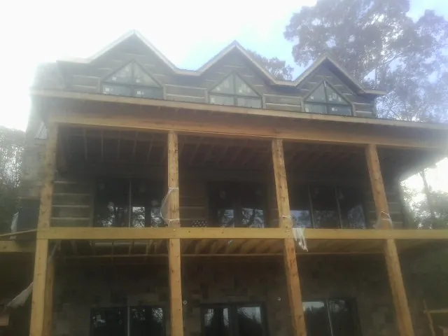Dormers and porch framing on a large log home under construction — Roof Coating work by our crew in Boylston