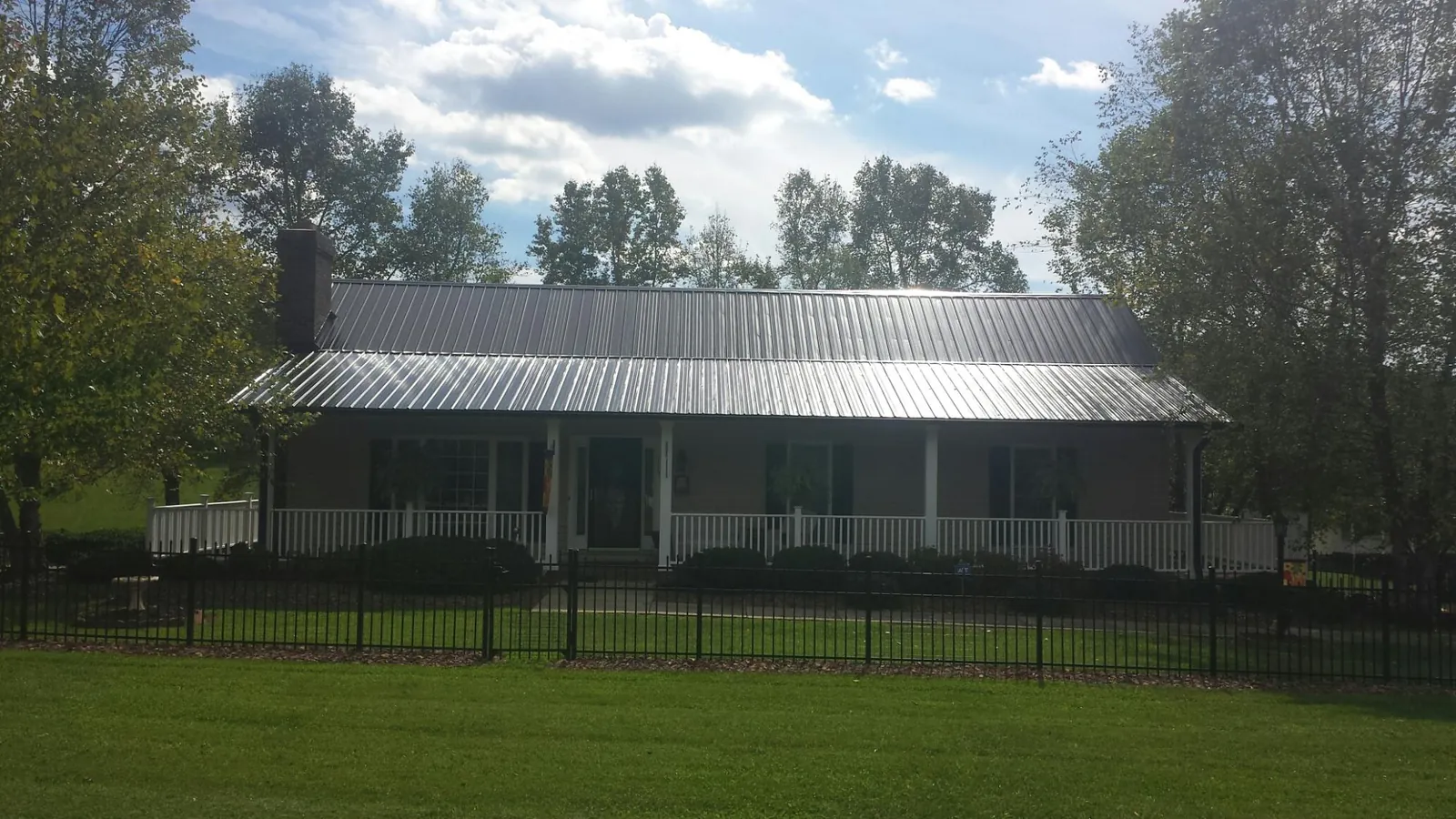 Gray metal roof on a brick ranch with a full width front porch — Gutter Guard Installation work by our crew in Boylston