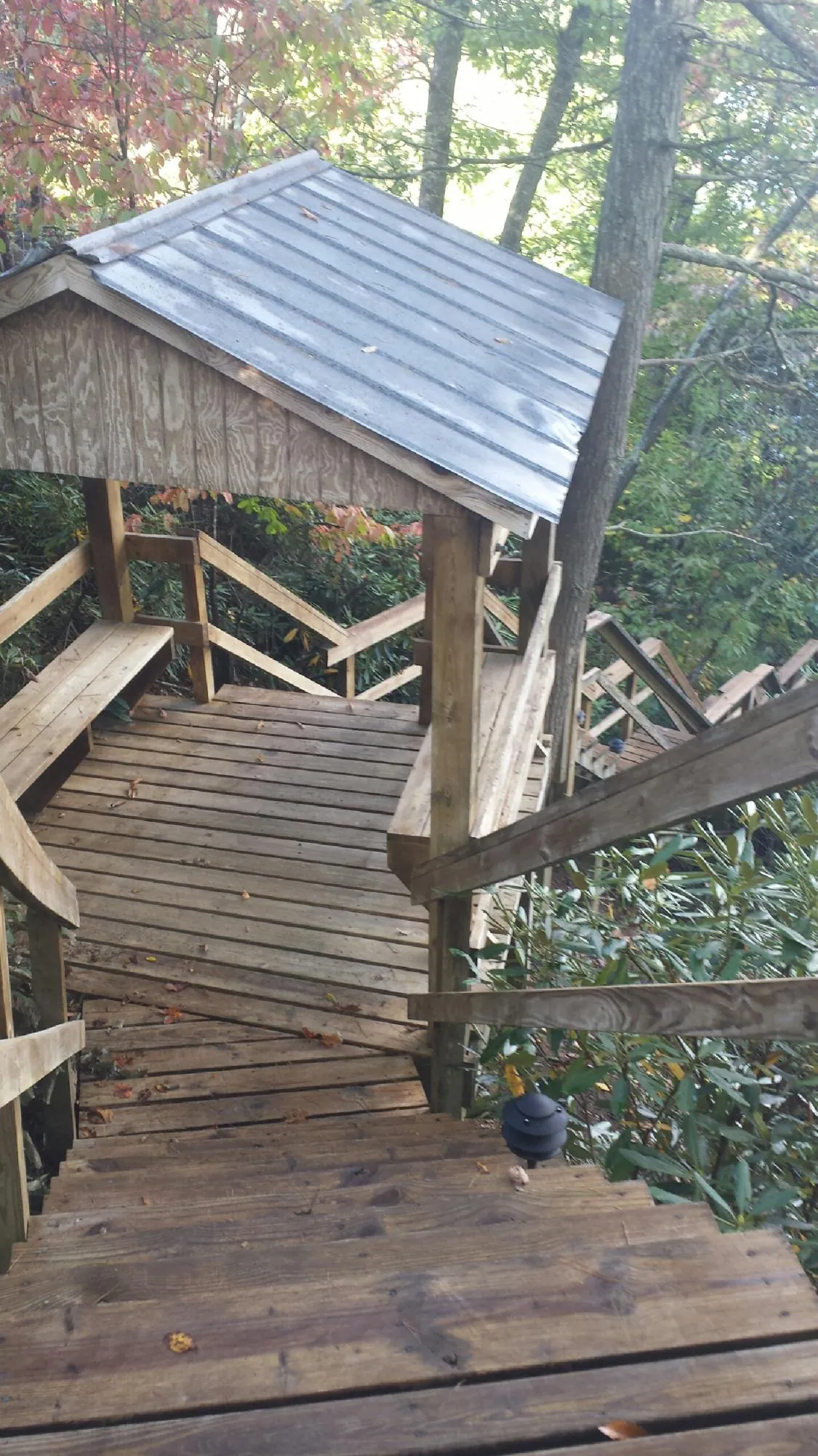 Metal roofed shelter over wooden steps on a wooded walkway — Skylight Repair & Installation work by our crew in Boylston