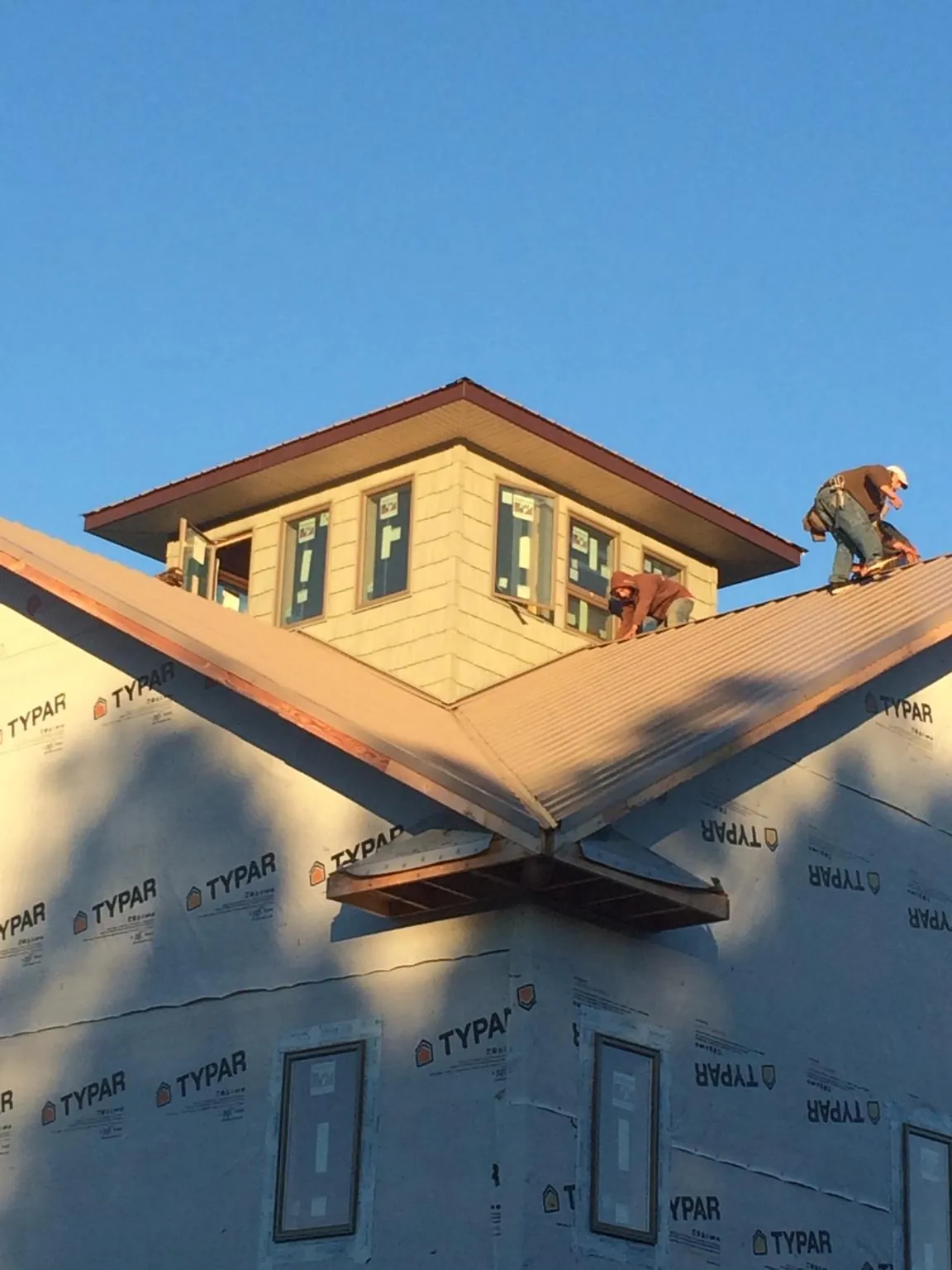 Roofers working around a rooftop cupola on a new metal roof at sunset — Roof Waterproofing in Boylston by Roofing Brothers